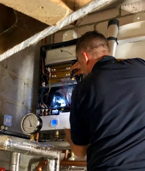 An Anglia Boiler engineer working on a wall-mounted boiler
